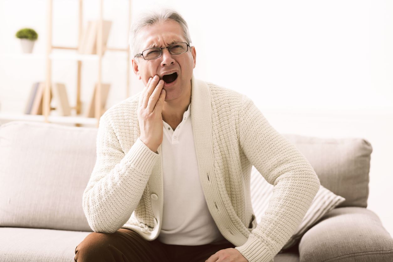 Man touching his jaw to symbolize signs of a cavity